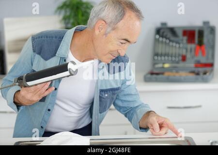 un uomo anziano che ripara la cucina Foto Stock