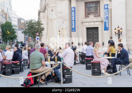 La gente gode del caldo clima autunnale in Covent Garden seduto fuori porta sul marciapiede zona salotto Londra Inghilterra Foto Stock