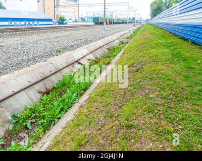 il canale di drenaggio della stazione ferroviaria non è stato pulito da molto tempo e viene coltivato con erba, fuoco selettivo Foto Stock