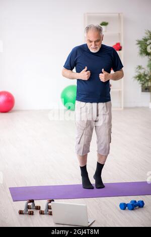 L'uomo anziano fa esercizi sportivi a casa Foto Stock