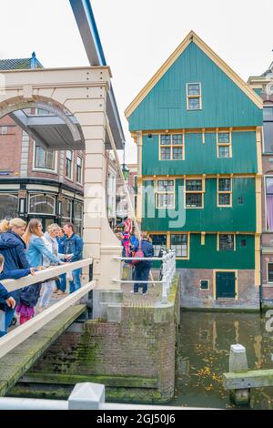 Alkmaar Olanda - Agosto 18 2012;i turisti affollano una passerella vicino a un edificio verde e giallo sul canale in questa pittoresca cittadina di bui olandesi Foto Stock