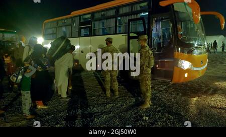 Soldati con la 127a compagnia militare di polizia, 759th MP Battaglione, 899 MP Brigade, aiutare gli evacuati afghani a bordo di un autobus su una base militare degli Stati Uniti in Kuwait 30 agosto 2021. L'autobus li ha presi per un controllo di sicurezza finale prima del loro volo per la destinazione successiva. (STATI UNITI Foto dell'esercito di Sgt. Connor Davis) Foto Stock