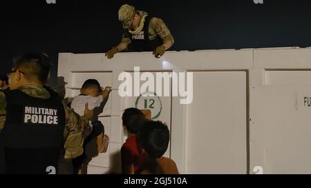 Soldati con la 127a compagnia militare di polizia, 759th MP Battaglione, 899 MP Brigade, recuperare un frisbee da un dumpster per i bambini afghani evacuati su una base militare degli Stati Uniti in Kuwait 30 agosto 2021. Poiché il processo di verifica per ciascuna famiglia ha richiesto diversi giorni, è stato importante mantenere gli immigrati in alto spirito durante questo periodo. (STATI UNITI Foto dell'esercito di Sgt. Connor Davis) Foto Stock