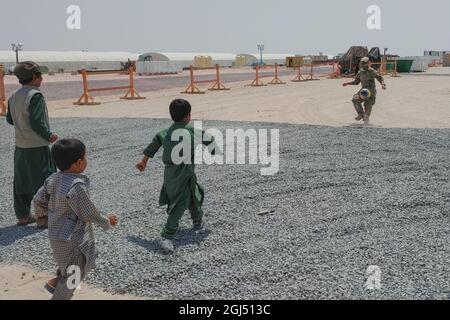 Soldati con la 127a compagnia militare di polizia, 759th MP Battaglione, 899 MP Brigade, giocare a calcio con gli evacuati afghani su una base militare degli Stati Uniti in Kuwait 31 agosto 2021. Poiché il processo di verifica per ciascuna famiglia ha richiesto diversi giorni, è stato importante mantenere gli immigrati in alto spirito durante questo periodo. (STATI UNITI Foto dell'esercito di Sgt. Connor Davis) Foto Stock