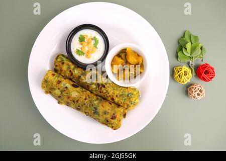 Un cibo chiamato Methi paratha o Methi thepla è un piatto indiano per la colazione servito con curd boondi raita e capsicum sabzi. Masala Fenugreek roti. Foto Stock