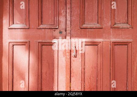 Vecchie porte di legno rosso sulla strada con riflessi luce del sole. Primo piano Foto Stock