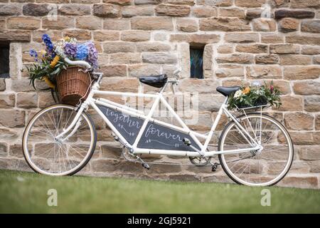 Matrimonio vintage vecchia bicicletta in tandem retro con segno appena sposato e fiori freschi in cesto tessuto. Bella bicicletta color bianco crema al luogo del matrimonio Foto stock Alamy