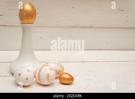 Uova di Pasqua dorate e vaso bianco su sfondo rustico vecchio legno. Composizione piatto Pasqua alla moda. Spazio di copia per il testo. Concetto di Pasqua minimo. EA Foto Stock