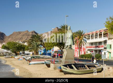 Barche da pesca tradizionali sulla spiaggia del porto e la statua di Diogo Alfonso, lo scopritore dell'isola. City Mindelo, un porto marittimo sull'isola Foto Stock