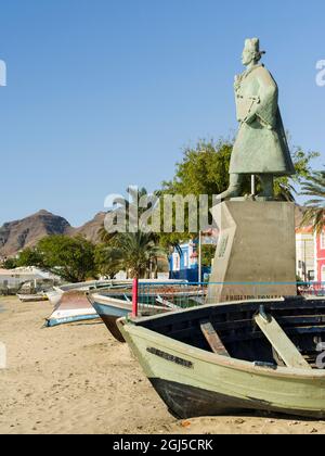 Barche da pesca tradizionali sulla spiaggia del porto e la statua di Diogo Alfonso, lo scopritore dell'isola. City Mindelo, un porto marittimo sull'isola Foto Stock