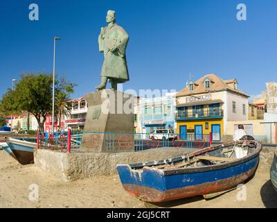 Barche da pesca tradizionali sulla spiaggia del porto e la statua di Diogo Alfonso, lo scopritore dell'isola. City Mindelo, un porto marittimo sull'isola Foto Stock