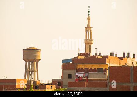 Egitto, il Delta del Nilo, tra Alessandria e il Cairo, skyline urbano su strada di appartamenti, minareto e torre d'acqua Foto Stock