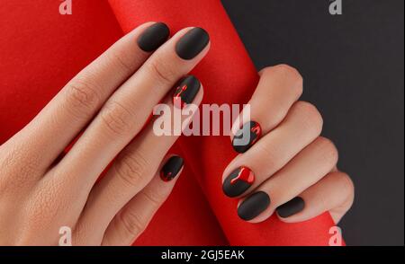 Mani femminili curate con accessori moda. Trendy autunno Halloween sanguinoso sparatutto chiodo design. Foto Stock