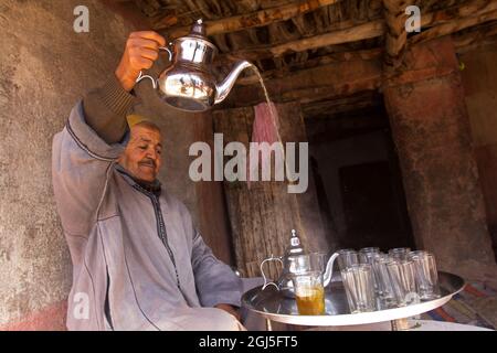 Africa, Marocco, Asni. L'uomo berbero versa il tè a casa nel villaggio di Asni nelle montagne dell'Atlante. Foto Stock