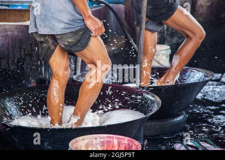Gli uomini che lavorano e schiappano nei bidoni di lavaggio in fabbrica di tessuti a Mandalay, Myanmar. Foto Stock