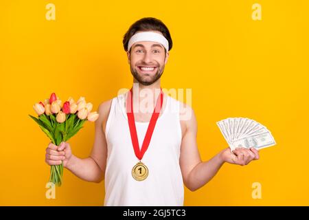 Ritratto di bel ragazzo allegro leader tenendo tulipani fan usd premio isolato su sfondo giallo brillante Foto Stock