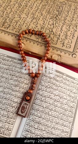 Un primo piano verticale di perle di preghiera sulle pagine aperte del Corano Foto Stock