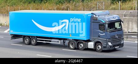 Vista laterale e frontale del camion grigio hgv Truck Blue catena di fornitura Amazon consegna articolata rimorchio driver e logo marchio pubblicità guida su autostrada UK Foto Stock