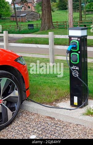 Primo piano rosso elettrico Jaguar auto e cavo elettrico collegato al bollard di ricarica una struttura al Warners Leisure Hotel Studley Warwickshire Inghilterra Regno Unito Foto Stock