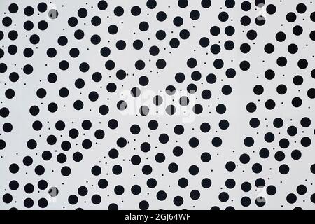 Primo piano astratto di sfondo bianco spotty del pannello di rivestimento dell'edificio dimensioni regolari piccolo circolare nero tondo puntini e casualmente piccole macchie Inghilterra UK Foto Stock