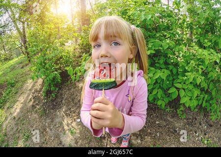 Una bambina mangia un grande lecca lecca Foto Stock