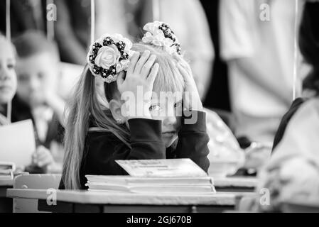 La prima volta che la ragazza si raduna a scuola si siede in un banco della scuola. Foto B W. Foto Stock