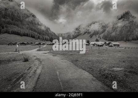 Scala di grigi di stretti sentieri che conducono a capanne in un villaggio Foto Stock