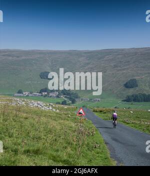 Ciclista femminile che scende a Halton Gill Road, Yorkshire Dales, Regno Unito. Foto Stock