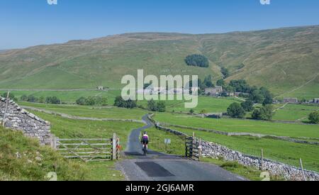 Ciclista femminile che scende a Halton Gill Road, Yorkshire Dales, Regno Unito. Foto Stock