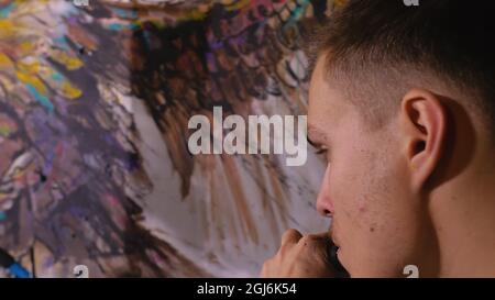 Artista designer disegna un aquila sulla parete. Artigiano arredatore dipinge un quadro con olio acrilico colore. Fumi Vaper vape. Pittore pittore vestito in Foto Stock