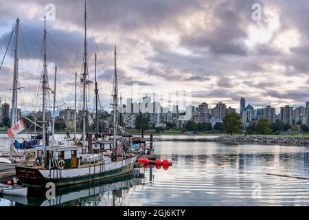 Barche a vela ormeggiate ad un molo a Kits Point, con vista dello skyline di Vancouver. Foto Stock