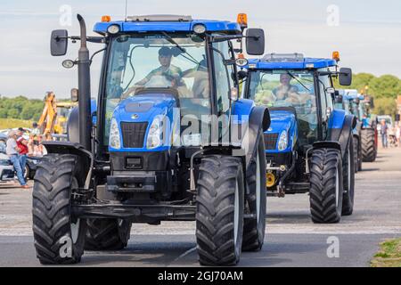 Una linea di trattori blu New Holland inizia un funzionamento di trattore, comunemente detenuti nelle aree rurali dell'Irlanda per raccogliere soldi per le associazioni di beneficenza. Foto Stock
