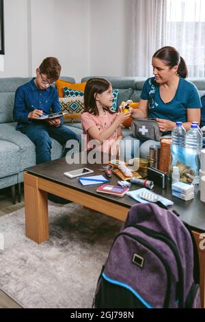 Madre che prepara lo zaino di emergenza con i suoi figli Foto Stock