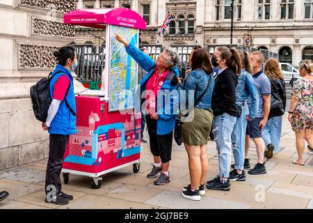 Team London Ambassadors aiutare i visitatori a Londra dandogli indicazioni su una mappa, Parliament Square, London, UK Foto Stock