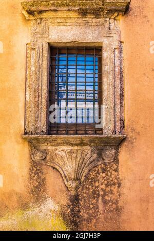 Italia, Sicilia, Provincia Di Trapani, Erice. Finestra barred con cornice in pietra decorativa su un edificio nell'antica città collinare di Erice. Foto Stock