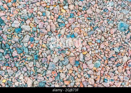 La tessitura di piccole pietre frantumate di diversi colori, su cui viene adagiato l'asfalto durante i lavori stradali Foto Stock