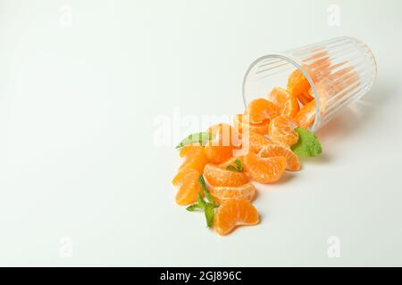 Concetto di produzione di succo di mandarino con bicchiere con mandarini su sfondo bianco. Foto Stock