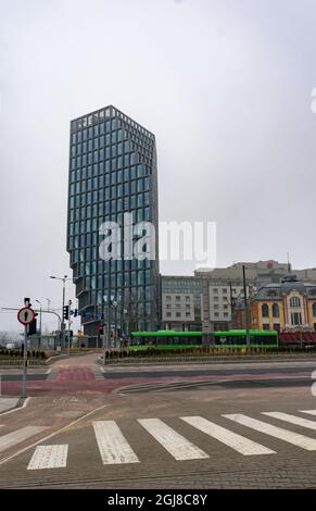 POZNAN, POLONIA - 14 feb 2018: Traversata Zebra con autobus verde di trasporto pubblico e edificio degli uffici sullo sfondo. Foto Stock