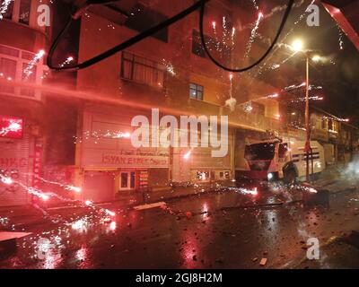 ISTANBUL 2014-05-22 manifestanti spara fuochi d'artificio. La polizia turca di sommosse usa un cannone ad acqua per disperdere i manifestanti durante una protesta contro il governo, a Istanbul, Turchia, il 22 maggio 2014. Un gruppo di manifestanti si è scontrato con la polizia di sommosse turca durante una protesta contro il governo turco che vede responsabile dell'esplosione della miniera di Soma. Secondo quanto riferito, l'AKP del primo ministro Recep Tayyip Erdogan ha respinto in aprile una mozione del Partito popolare Repubblicano (CHP) di centro-sinistra per rivedere la sicurezza nella miniera di Soma. La peggiore catastrofe mineraria della storia del paese ha lasciato almeno 301 lavoratori morti. Foto di Foto Stock