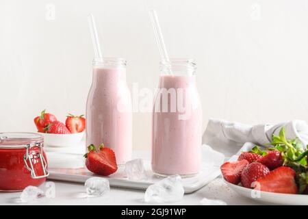 Tradizionale ayurvedico sano indiano fragola lassi o milkshake in bottiglie su uno sfondo bianco. Foto Stock