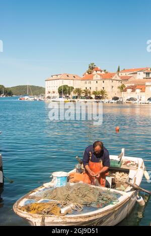 Europa, Croazia, Brac, Milna. Il pescatore pulisce le reti dopo la cattura di mattina Foto Stock