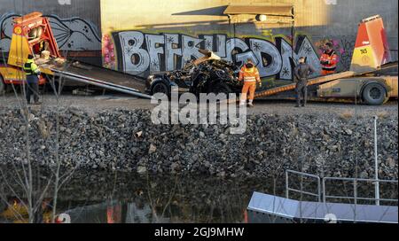 ** NUOVE INFORMAZIONI! I cinque uomini uccisi nel ponte auto crash sono stati cittadini britannici ** SODERTALJE 2016-02-13 Una macchina gravemente danneggiata è trainata dal canale sotto il ponte autostradale E4 a Sodertalje, Svezia, 13 febbraio 2016. La polizia di domenica ha confermato che i cinque uomini uccisi quando la loro auto ha attraversato il cancello e volato fuori dal ponte autostradale aperto 29 metri di altezza presto Sabato mattina sono cittadini britannici. Il ponte era stato aperto per permettere ad una nave da carico di passare sotto di esso e altre auto si erano fermate davanti al cancello e luci rosse. È in corso un'indagine sul motivo per cui la vettura in crash non è riuscita a fermarsi. Foto: Foto Stock