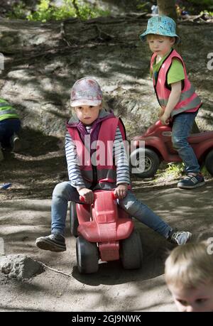 STOCCOLMA 20150528 Una ragazza e un ragazzo stanno cavalcando un'auto giocattolo in un parco giochi Foto Jonas Ekstromer / TT / kod 1003 play ground, telaio di arrampicata, Foto Stock