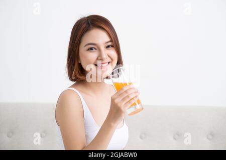 Ritratto di una ragazza casual carino bere succo d'arancia da un bicchiere Foto Stock