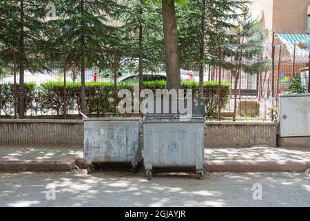 Contenitori di rifiuti sotto gli alberi su una strada a Istanbul. Spazio per la copia Foto Stock