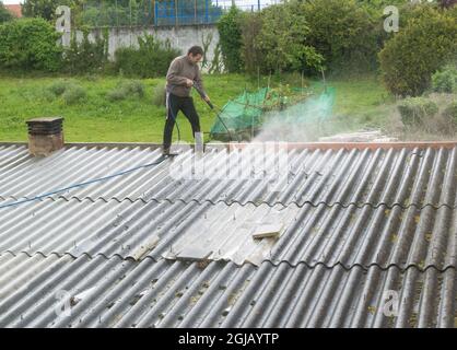 Uomo sopra un tetto pulirlo con acqua pressurizzata Foto Stock