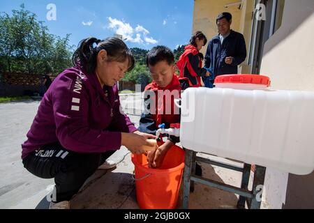 (210909) -- PINGSHUN, 9 settembre 2021 (Xinhua) -- li Yuemei (1st L) aiuta uno studente a lavarsi le mani prima di pranzo al sito di insegnamento di Datuo nel villaggio di Datuo, Contea di Pingshun, Changzhi Città della Provincia di Shanxi della Cina settentrionale, 7 settembre 2021. Immerso nel monte Taihang ad un'altitudine di 1,600 metri nella contea di Pingshun, il sito didattico di Datuo è l'unica struttura educativa a 10 chilometri di distanza. La canzone Zhongsheng e sua moglie li Yuemei, l'unica facoltà del sito, lavorano lì per 16 anni di seguito, attualmente rendendo i loro servizi a soli cinque studenti di varie epoche.A. Foto Stock