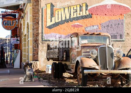 Lowell, Arizona. Cane e vecchio arrugginito pick-up camion di fronte a un murale per la città di Lowell. Foto Stock