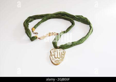 Collana in tessuto verde con Allah scrittura alla fine. Isolato sfondo bianco Foto Stock