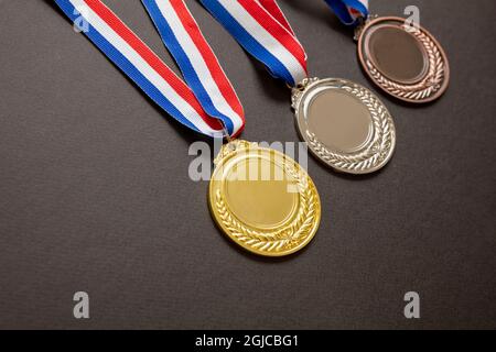 Medaglie, oro, argento e bronzo. Vincitori, premio atleti podio concetto trofeo. Primo, secondo e terzo posto premio appeso al nastro rosso blu o Foto Stock